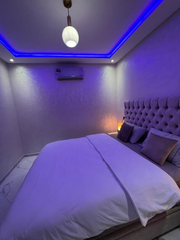 a bedroom with a large bed with a blue lighting at Appartement Wow in Al Hoceïma