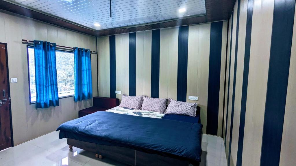 Un dormitorio con una cama azul con rayas azules y blancas en Triyugi Heights cottage sitapur, en Trijugi Nārāyan