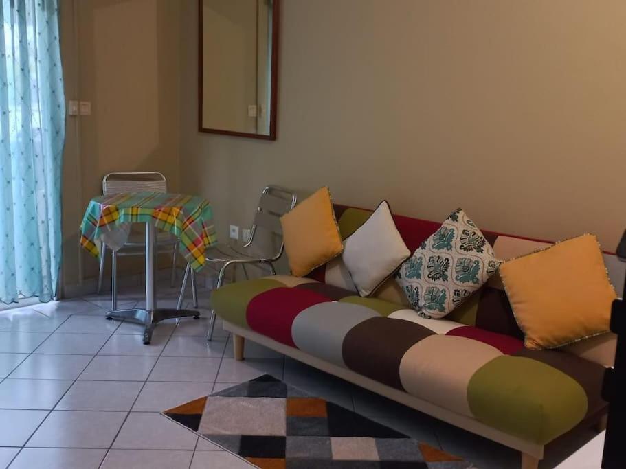 - un canapé avec des oreillers colorés dans le salon dans l'établissement Appartement cosy avec chambre, à Marigot