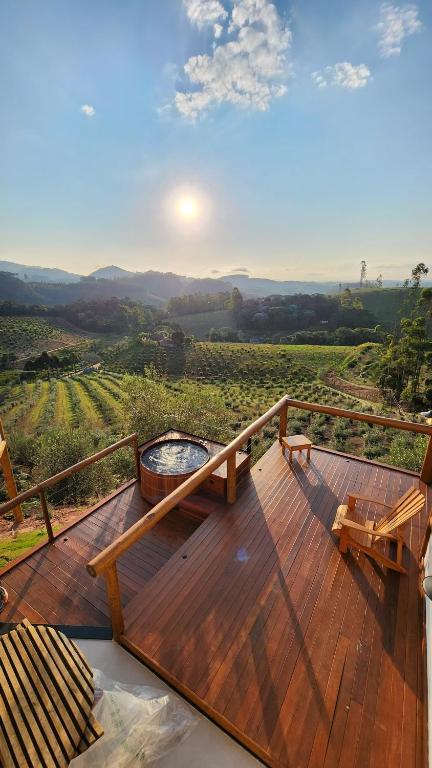 a deck with a grill and a view of a vineyard at Chalés Monte das Oliveiras in Domingos Martins