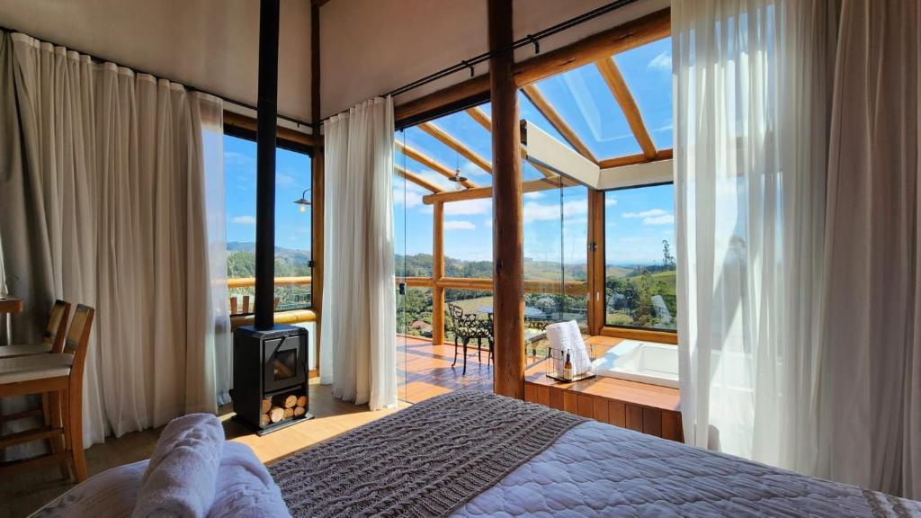 um quarto com uma cama e uma grande janela em Chalés Monte das Oliveiras em Domingos Martins