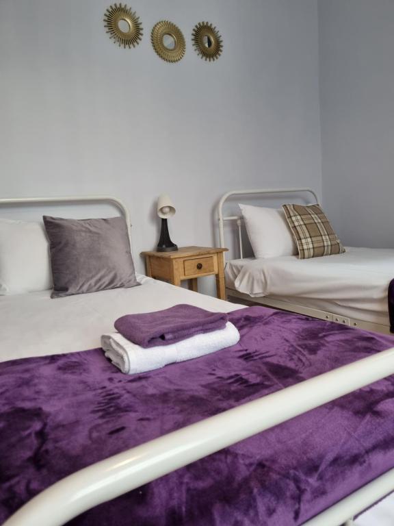 two beds with purple sheets and towels on them at The Windmill Hotel in London