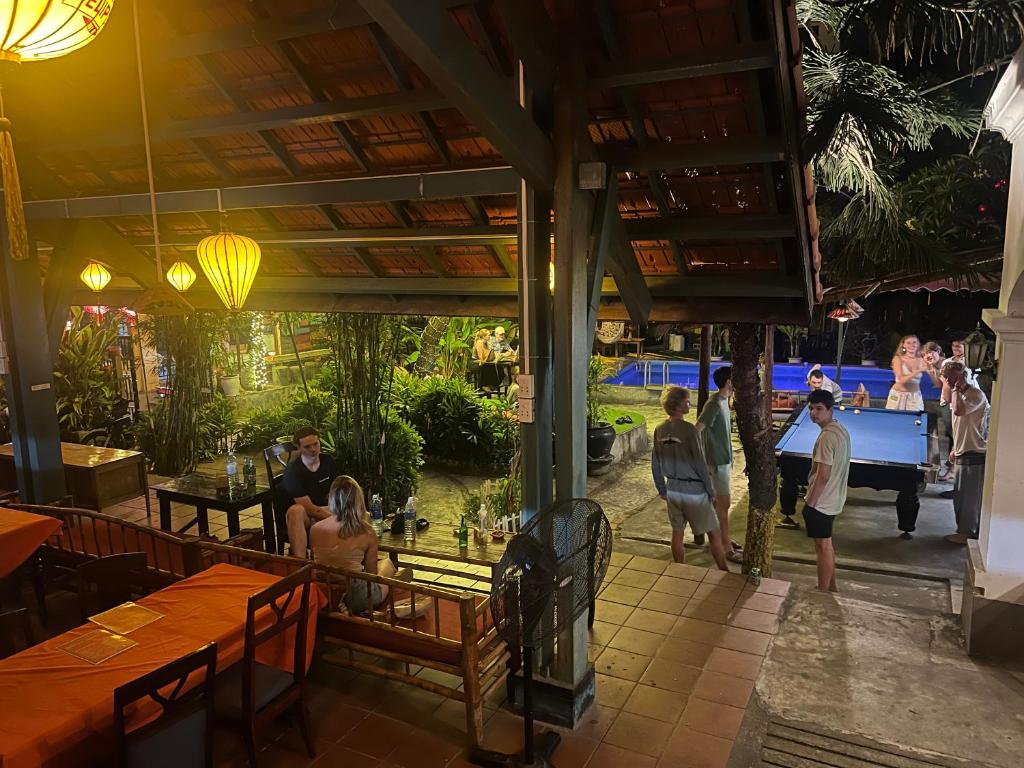 a group of people walking around a restaurant at Heliport Hostel in Hoi An
