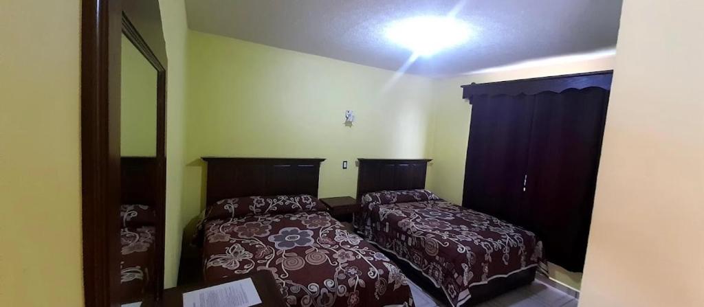 a bedroom with two beds and a mirror at Hotel curvita in San Cristóbal