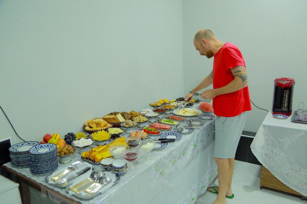 a man standing in front of a table with food at Boulevard Architectural Hotel in Bukhara