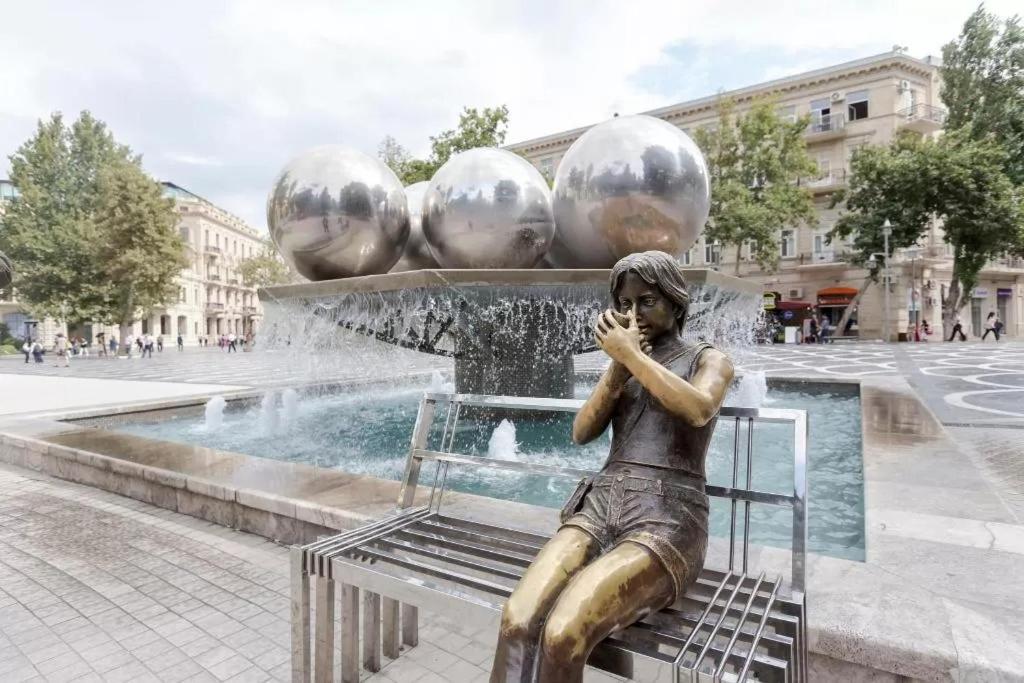 a statue of a boy sitting on a bench in front of a fountain at Pak Az Deluxe Hotel in Baku