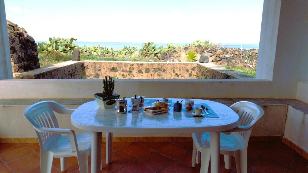 uma mesa com cadeiras e uma mesa com comida em Elio&Mina - appartamento con vista mare em Pantelleria