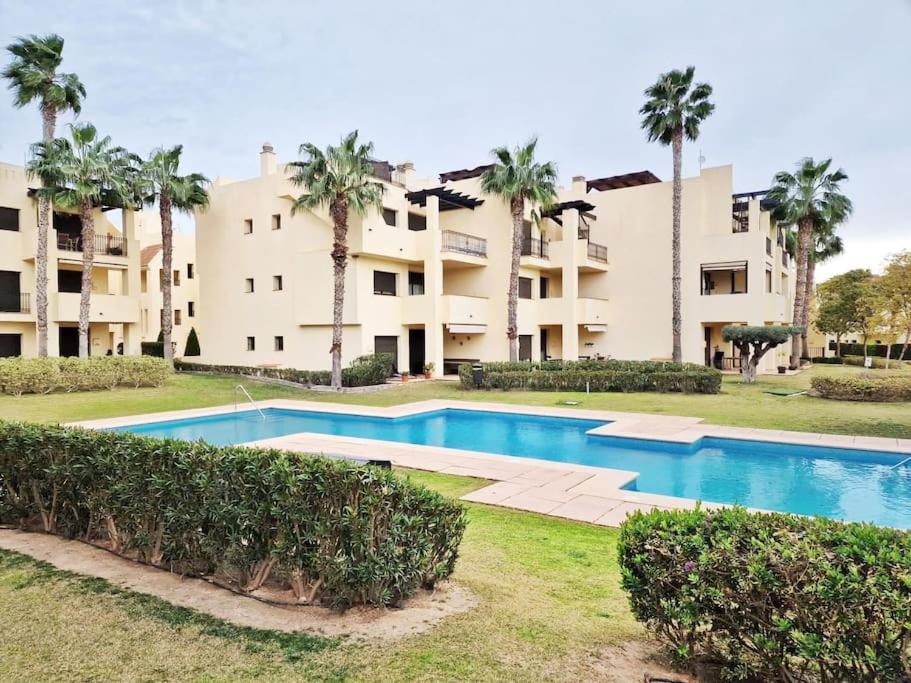 a swimming pool in front of a building with palm trees at Apto. Residencial Poniente en San Javier in San Javier