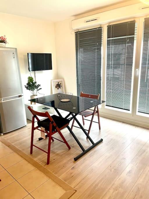 un salon avec une table et un réfrigérateur dans l'établissement Cosy Studio proche de Paris idéal pour les JO, à Argenteuil