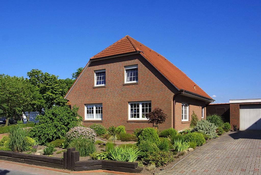 a large brick house with a pitched roof at Ferienwohnung Lena in Stedesdorf bei Esens an der Nordseeküste in Ostfriesland in Stedesdorf