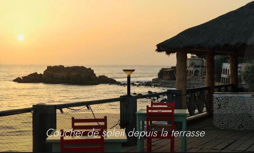 un tavolo e sedie sulla spiaggia al tramonto di B and B Pieds dans l'eau a Poponguine