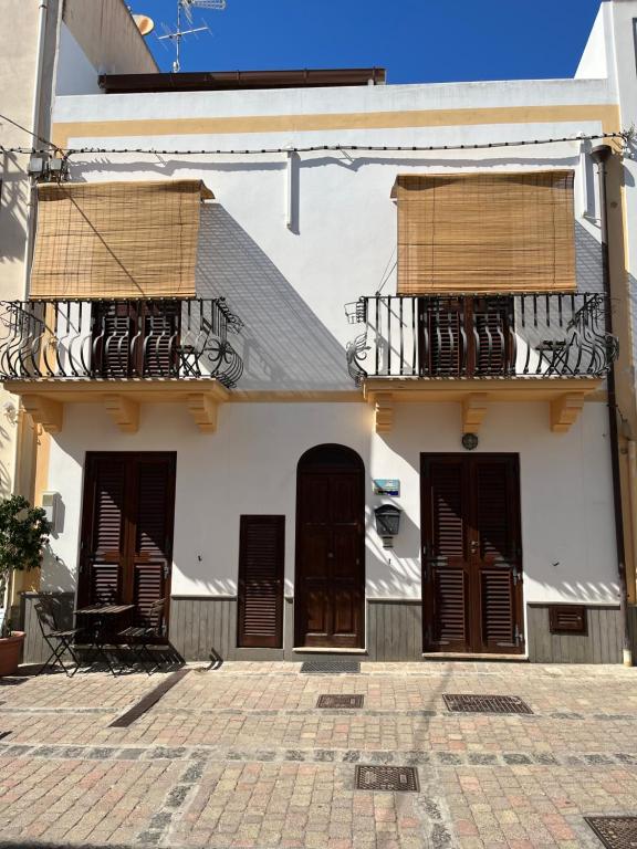 ein weißes Gebäude mit zwei Balkonen und zwei Türen in der Unterkunft Casa Maruzzella in Lipari