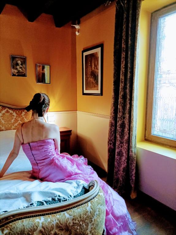 une femme assise sur un lit donnant sur une fenêtre dans l'établissement Une nuit au manoir Thiers mode hanté possible gratuitement, à Thiers