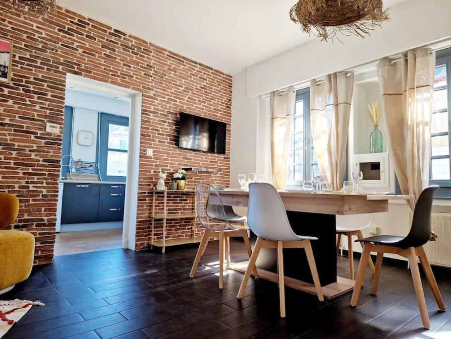 ein Wohnzimmer mit einer Ziegelwand, einem Tisch und Stühlen in der Unterkunft Haut Foirail, Balcon Centre-Ville in Espalion