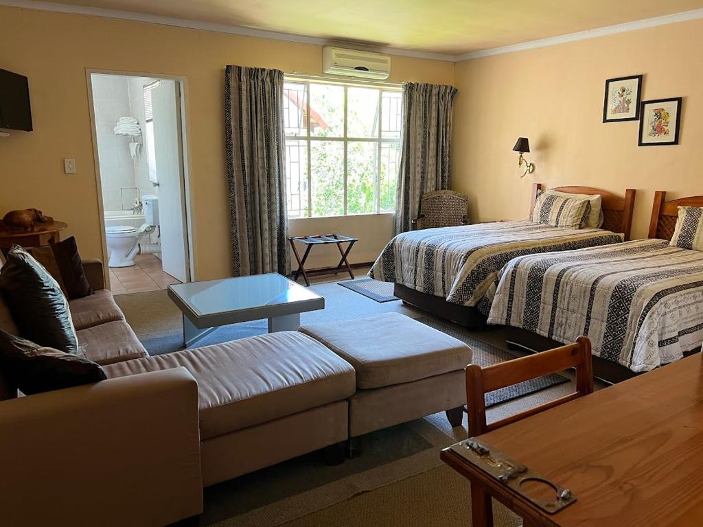 a living room with two beds and a couch at Ipe Tombe Guest Lodge in Midrand