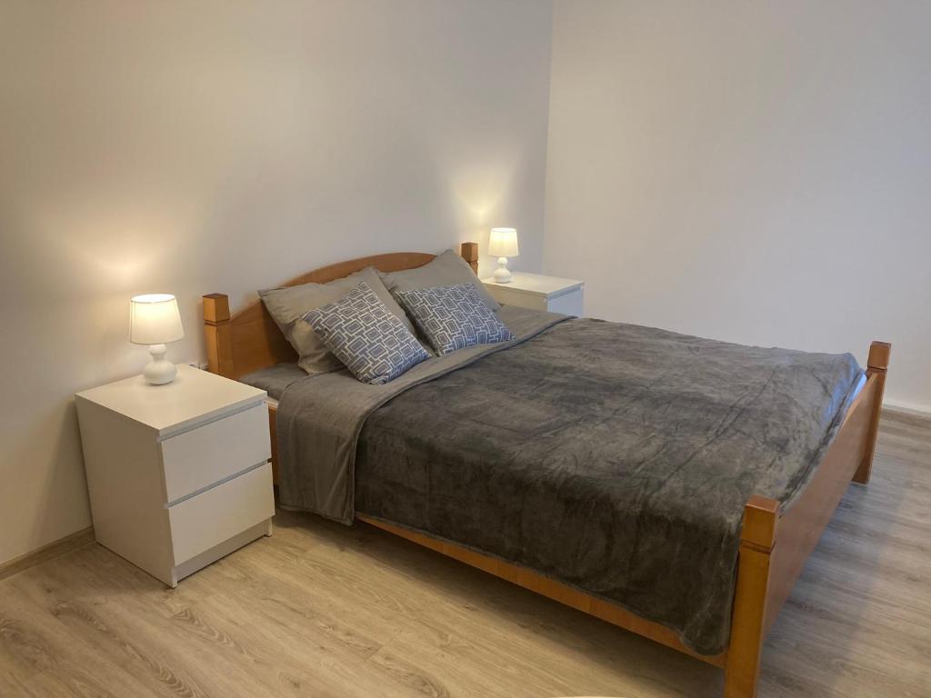 a bedroom with a bed with two night stands and two lamps at Apartament Kopytko in Bielsko-Biała