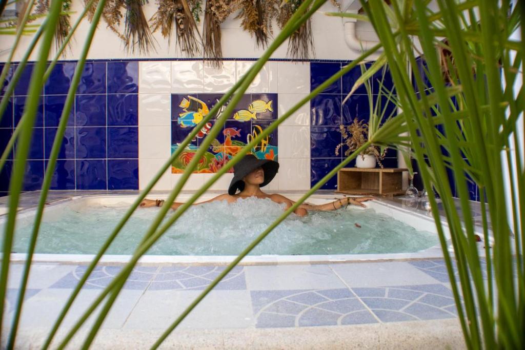 una mujer en una piscina con sombrero en Selva María Hotel Boutique, en Santa Fe de Antioquia