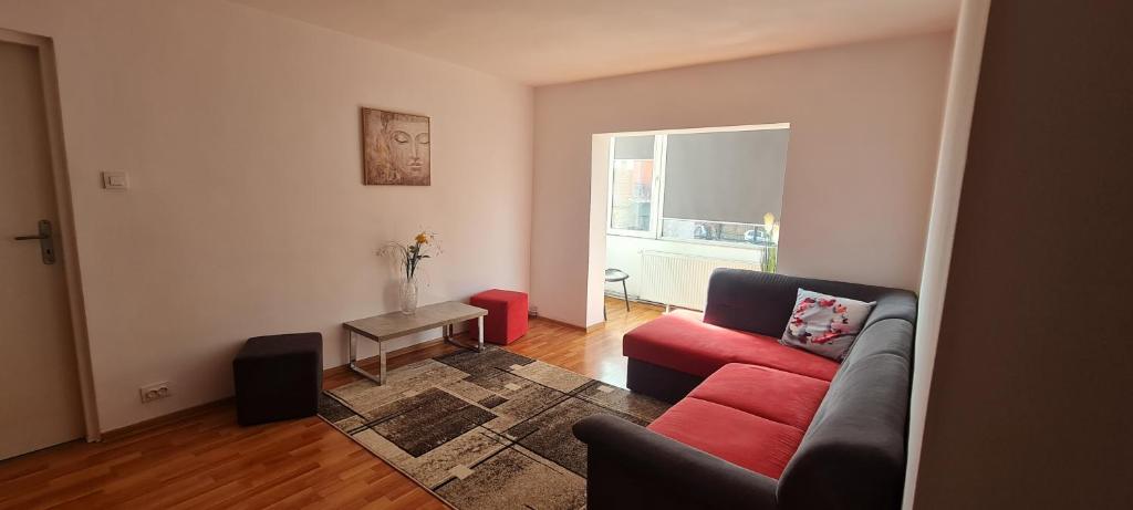 ein Wohnzimmer mit einem roten Sofa und einem Fenster in der Unterkunft La Bloc Apartment in Arad