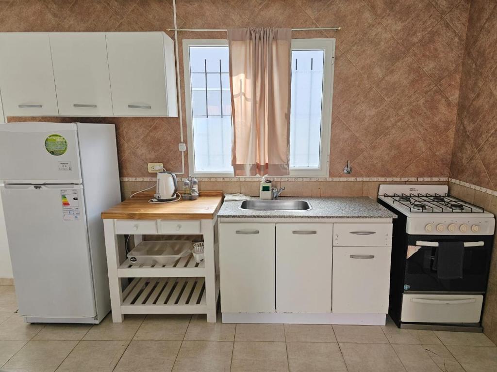 エル・カラファテにあるAlameda Apartのキッチン(白いキャビネット、白い冷蔵庫付)