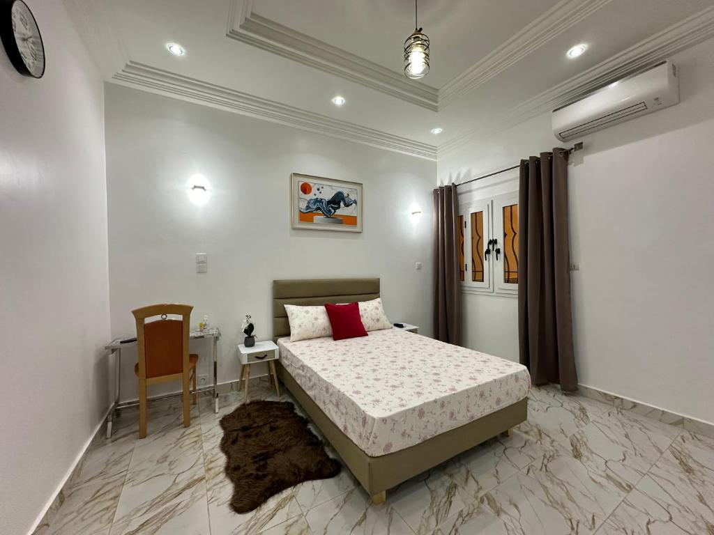 1 dormitorio con 1 cama, 1 mesa y 1 silla en Kyra’s place, en Rufisque