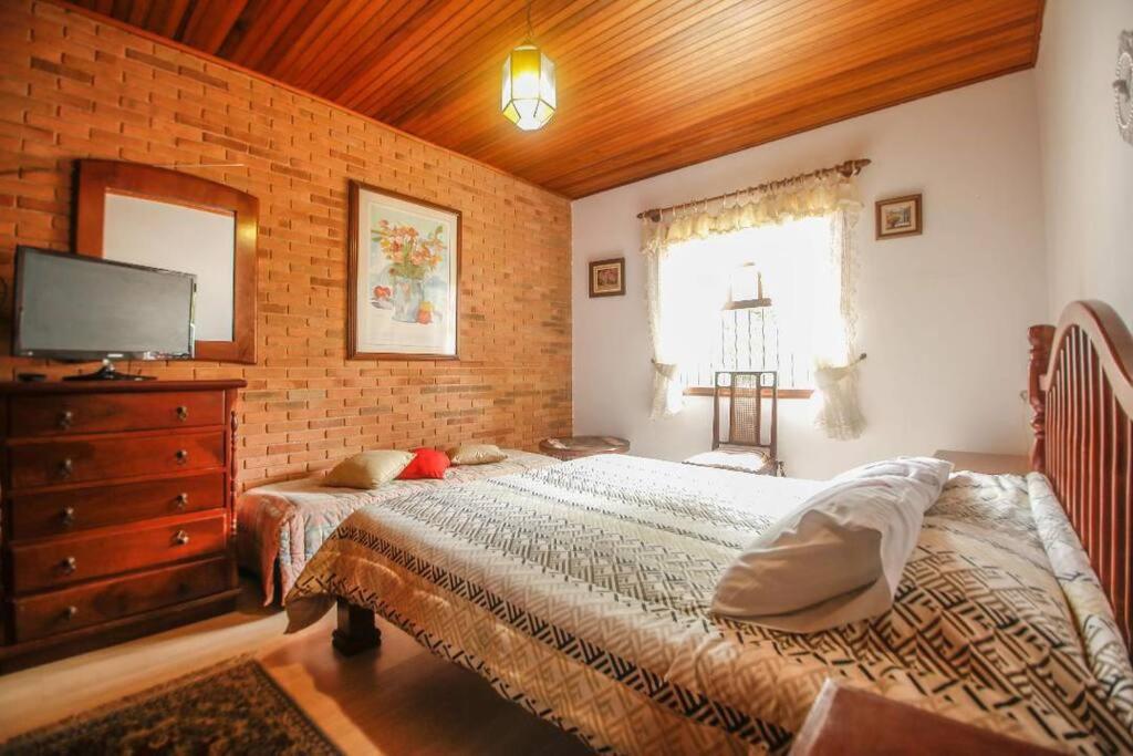 a bedroom with a bed and a dresser with a television at Suítes para locação próximo ao Capivari in Campos do Jordão