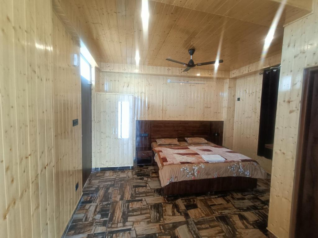 - une chambre avec un lit dans une pièce dotée de murs en bois dans l'établissement Ramandeep Stays, à Dharamshala