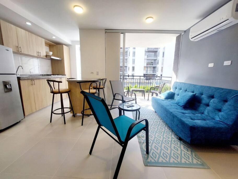 a living room with a blue couch and a kitchen at Acogedor Apartamento en Ricaurte, Cundinamarca in Girardot