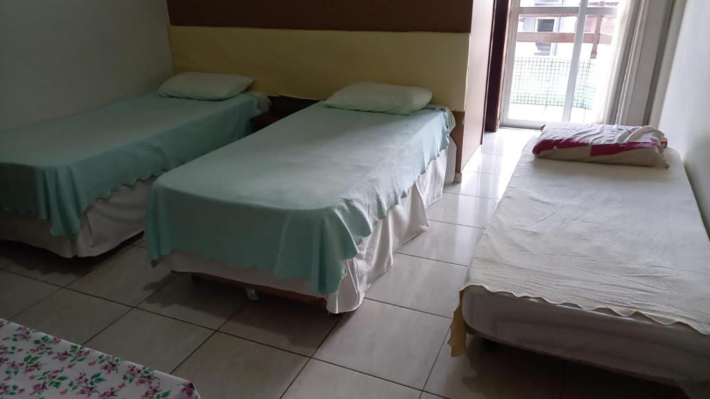 3 Betten in einem Zimmer mit Fenster in der Unterkunft Espaço Verona-Apartamento triplo com banheiro e sem café in Fazenda Rio Grande