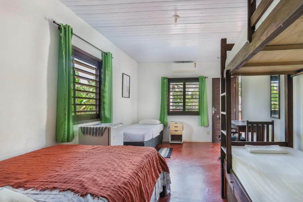a bedroom with two beds and green curtains at No Worries Pipa in Pipa