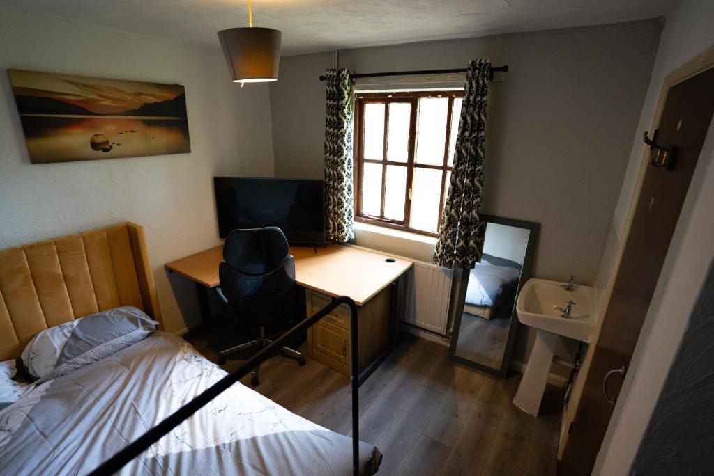 Sevenoaks Guest House في Trimley Heath: غرفة نوم بسرير ومكتب ونافذة