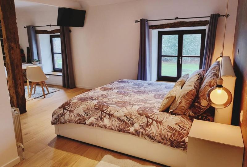 a bedroom with a bed in a room with windows at L'Essentiel bis in Francorchamps