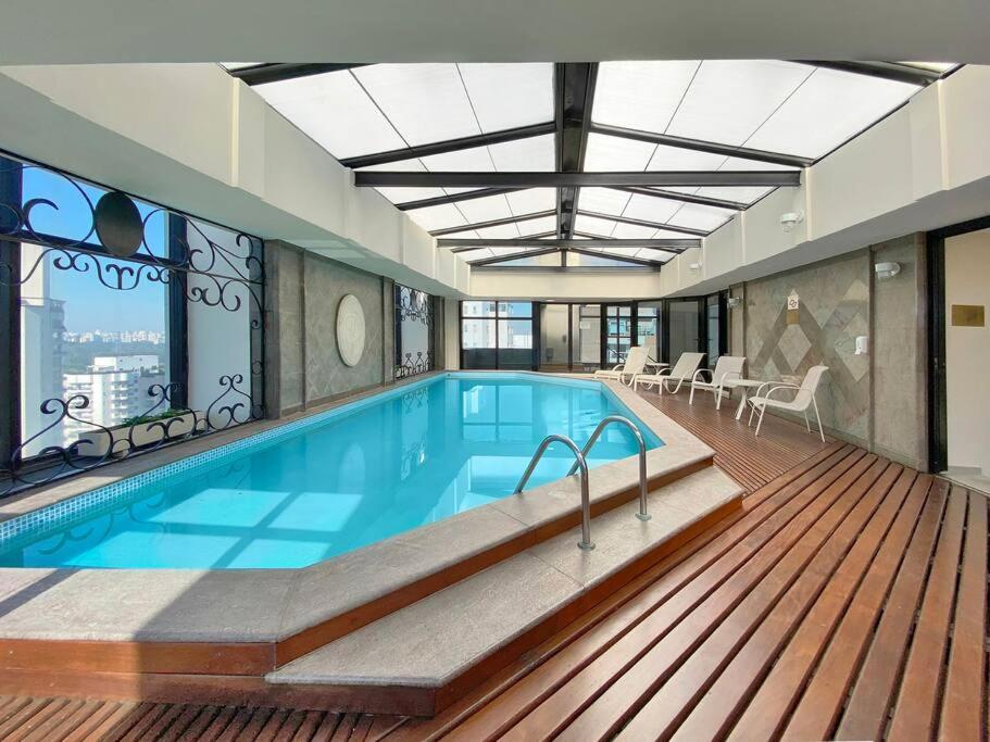 a large swimming pool in a building with a deck at Apart-hotel 1804 - Le Premier Suítes Jardim Paulista in Sao Paulo