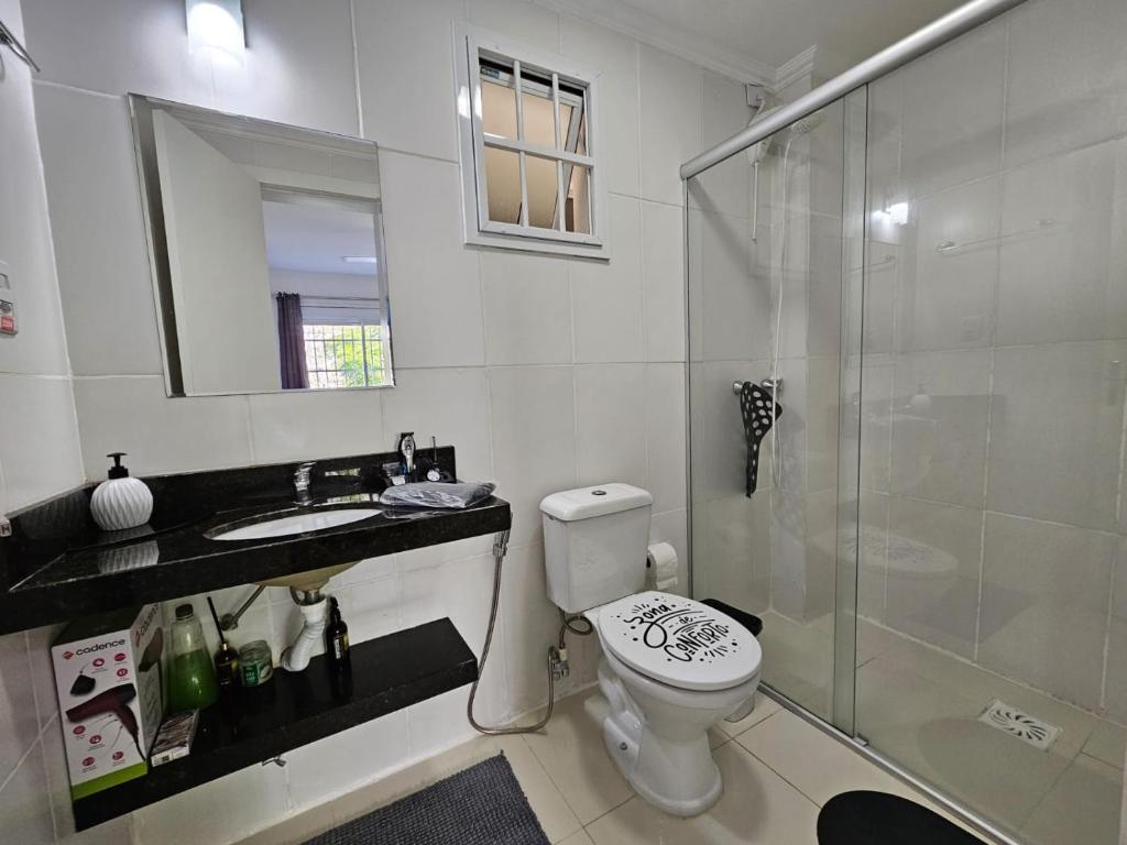 La salle de bains est pourvue de toilettes, d'un lavabo et d'une douche. dans l'établissement Apartamento centralizado à poucas quadras do mar., à Tramandaí