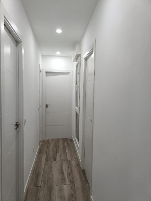 an empty hallway with a white door and wooden floors at Habitaciones plaza payor in Madrid