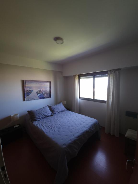 um pequeno quarto com uma cama e uma janela em Departamento Playa Grande Alem Golf em Mar del Plata