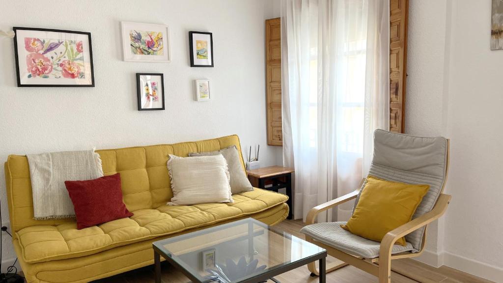 a living room with a yellow couch and a chair at El Patio de Wallada in Córdoba