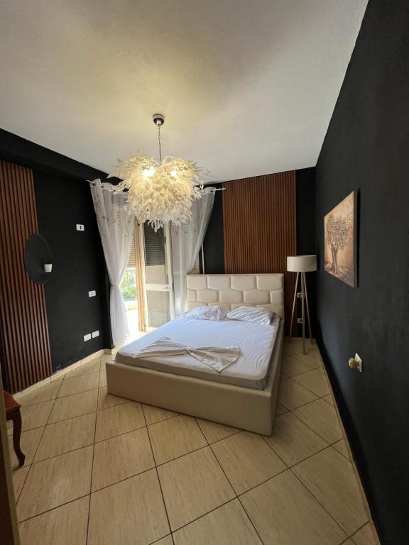 a bedroom with a large bed and a chandelier at Bega's Apartment in Golem, Durrës in Golem