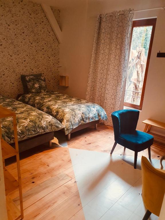 a bedroom with two beds and a chair and a window at Chambres d&#39;Hôtes du Domaine de Bourbacoup in Tulle