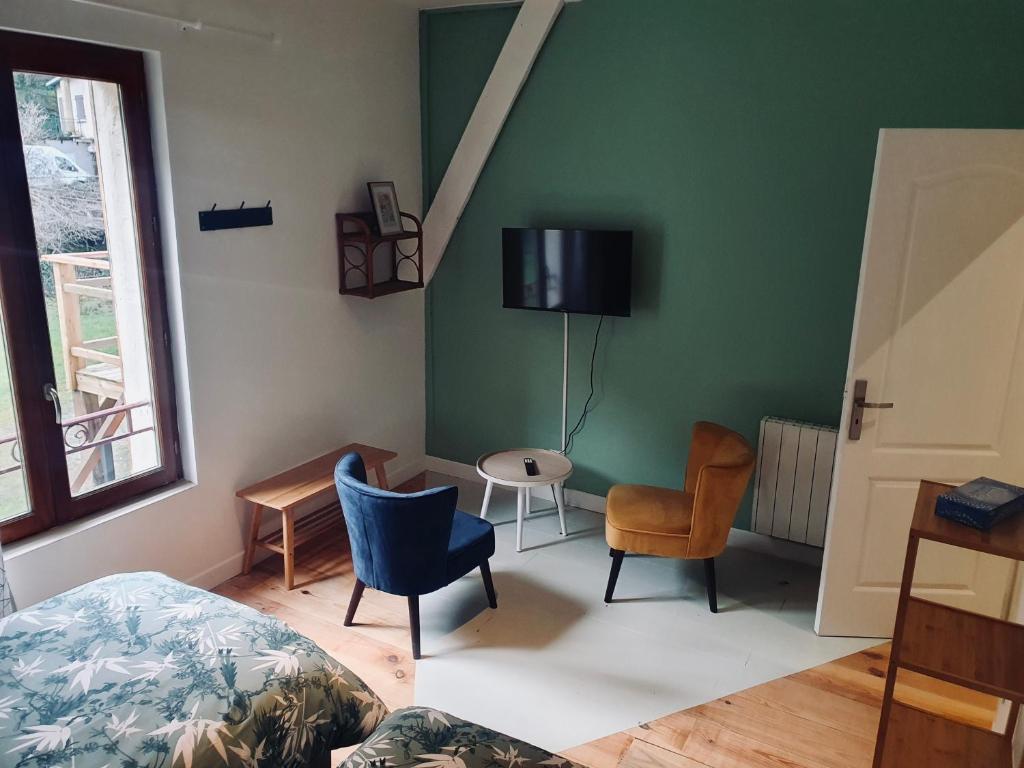 a bedroom with a bed and chairs and a tv on the wall at Chambres d&#39;Hôtes du Domaine de Bourbacoup in Tulle