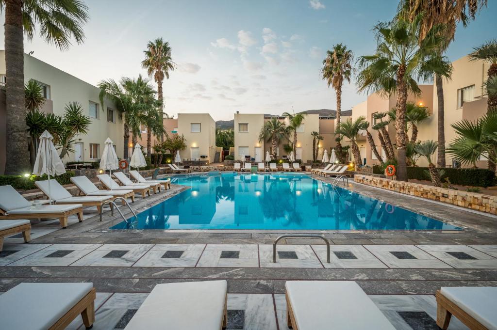 una piscina en el complejo con tumbonas y palmeras en Meropi Hotel & Apartments en Malia