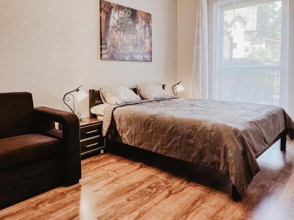 um quarto com uma cama, uma cadeira e uma janela em Apartament 7 em Szklarska Poręba