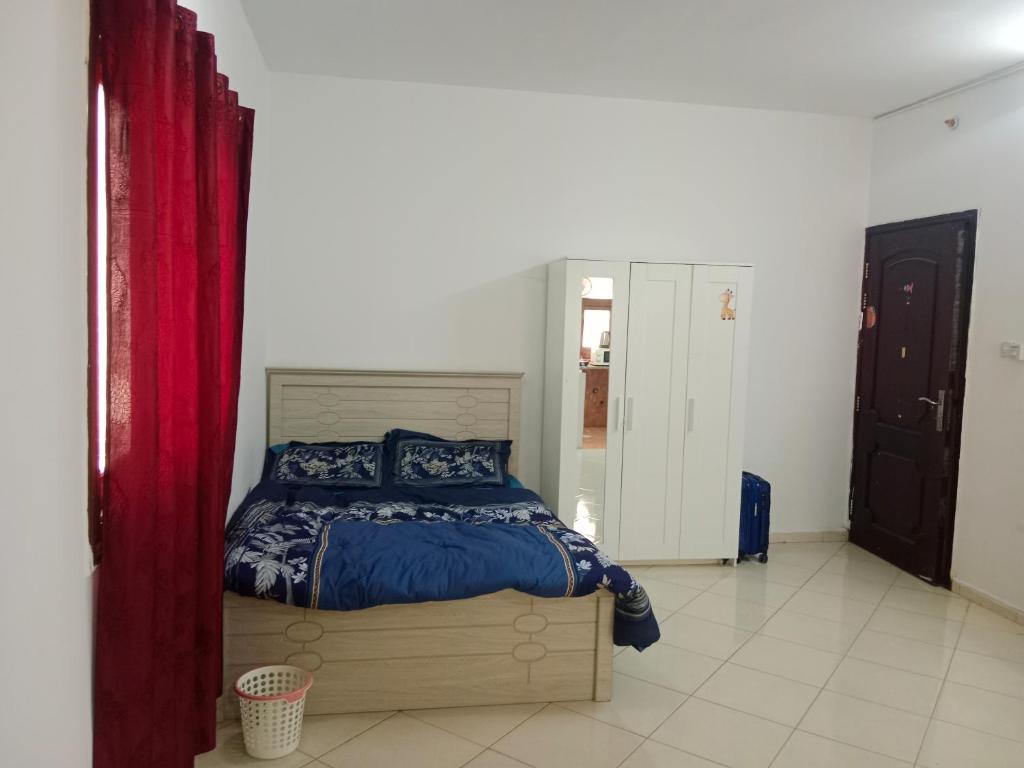 a bedroom with a bed and a red curtain at Family Studio Apartment in Sharjah