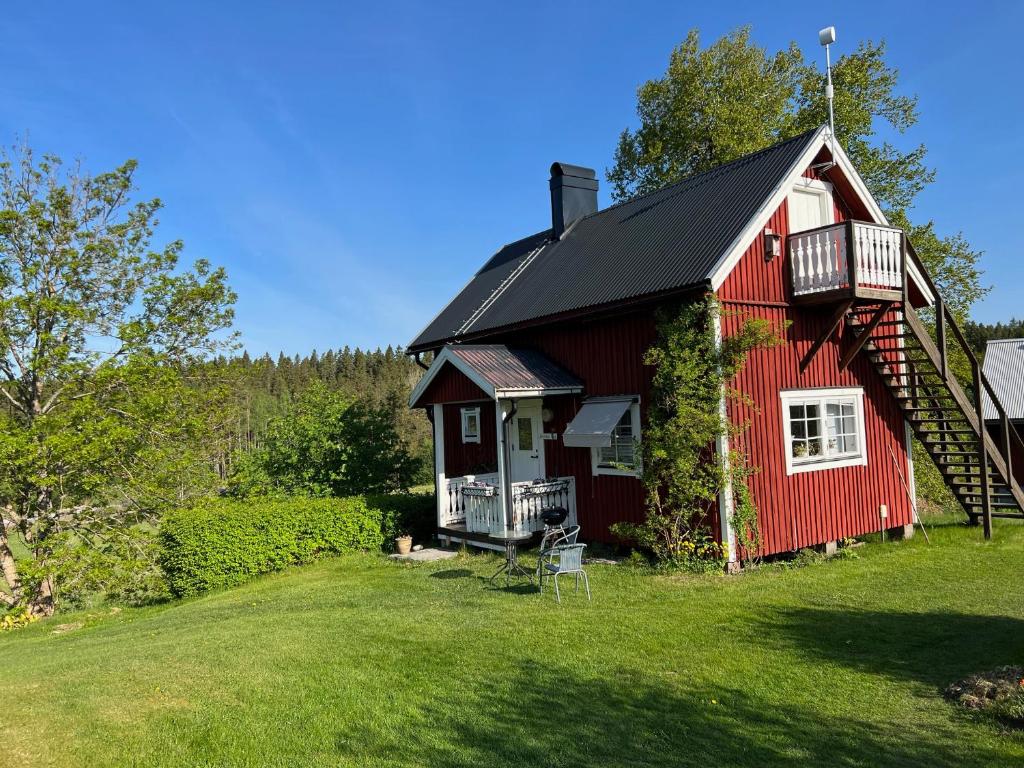 una casa roja con techo negro en un patio en Annies Hus en Årjäng