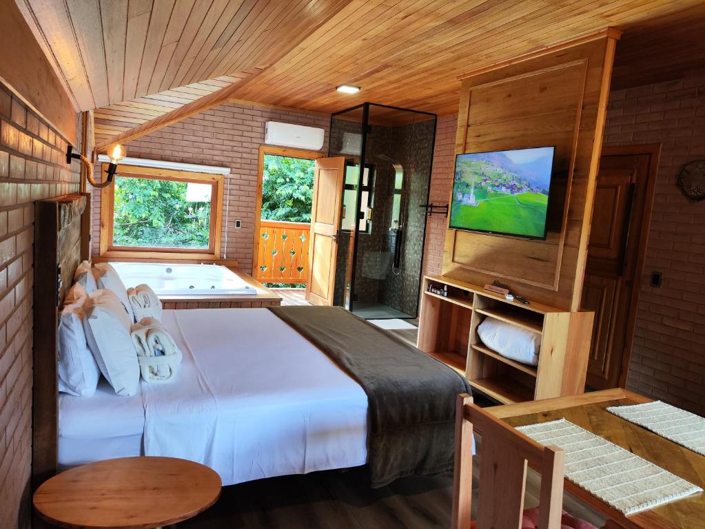a bedroom with a bed with a tub and a television at Sonnen Schein Chalés in São Martinho