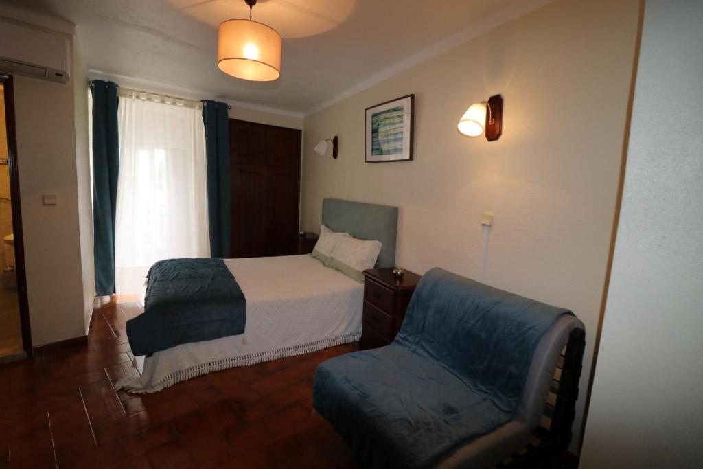 um quarto com uma cama, uma cadeira e uma janela em Residencial Miguel José em Estremoz