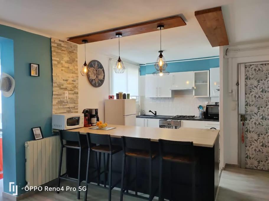 eine Küche mit blauen Wänden und einer Theke mit Barhockern in der Unterkunft Grand T2 esprit loft Cœur de Ville in Sète