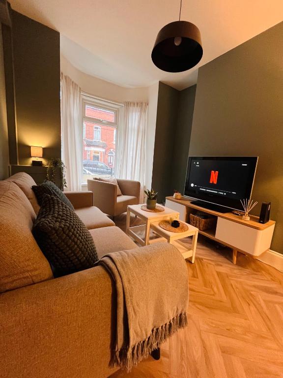 uma sala de estar com um sofá e uma televisão de ecrã plano em Kings Bridge Townhouse em Belfast