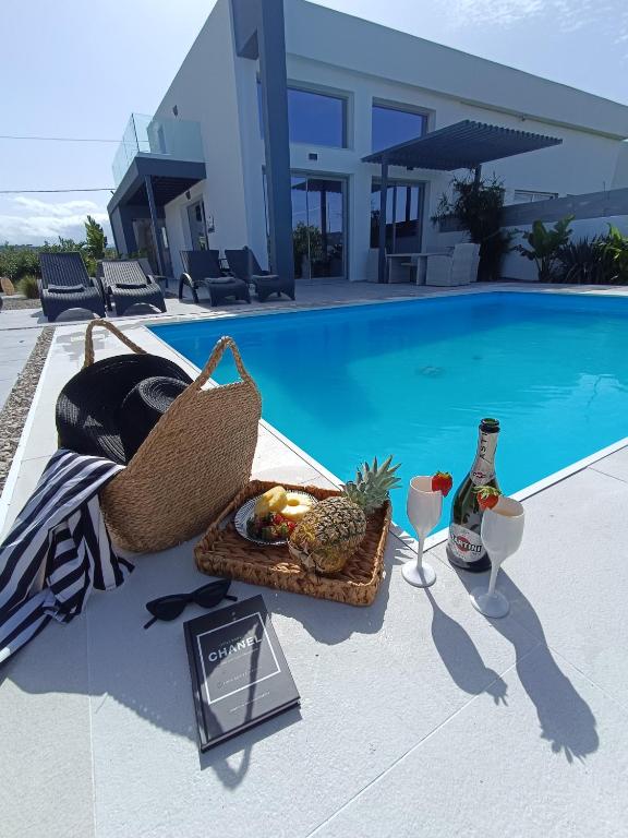 a basket of fruit and a bottle of wine next to a pool at Casa di Rea Sanfilippo in Soroni