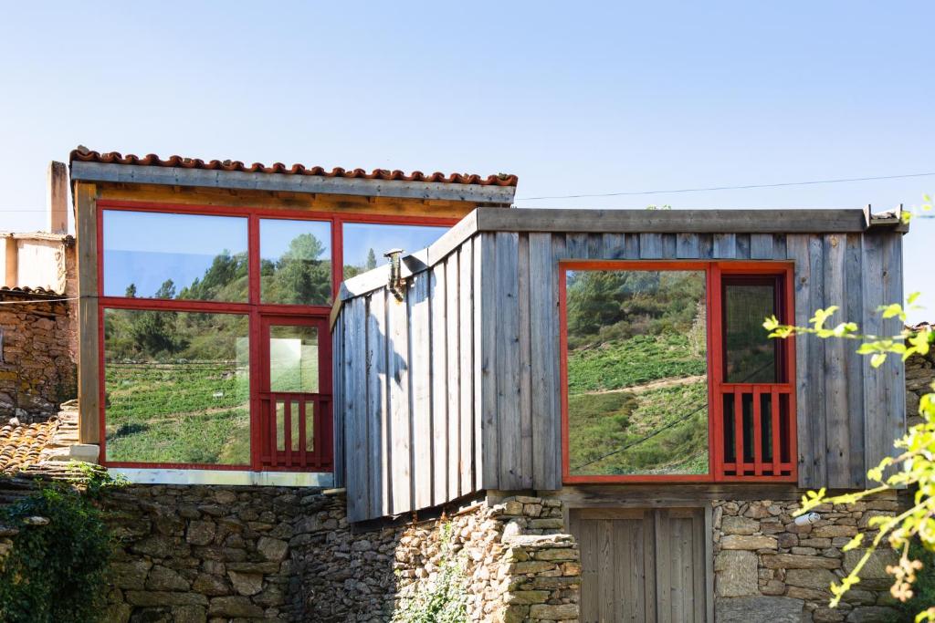um edifício de madeira com três janelas numa parede de pedra em Casa do Lecer em La Teijeira