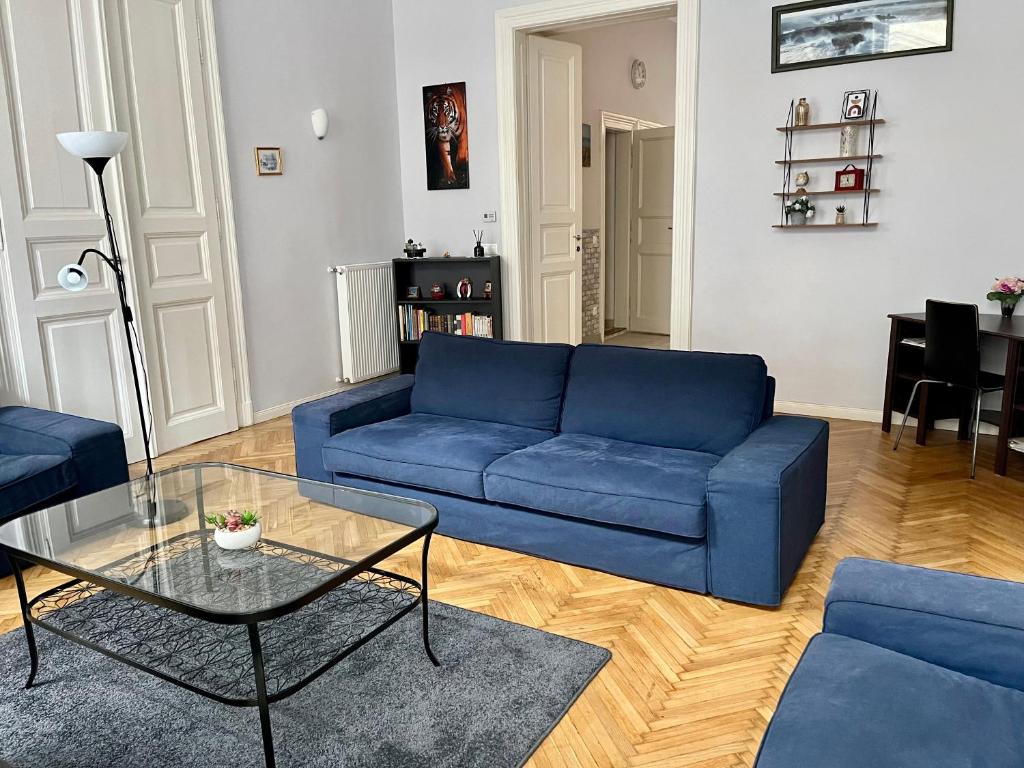 uma sala de estar com um sofá azul e uma mesa de vidro em Rackozi apt em Budapeste